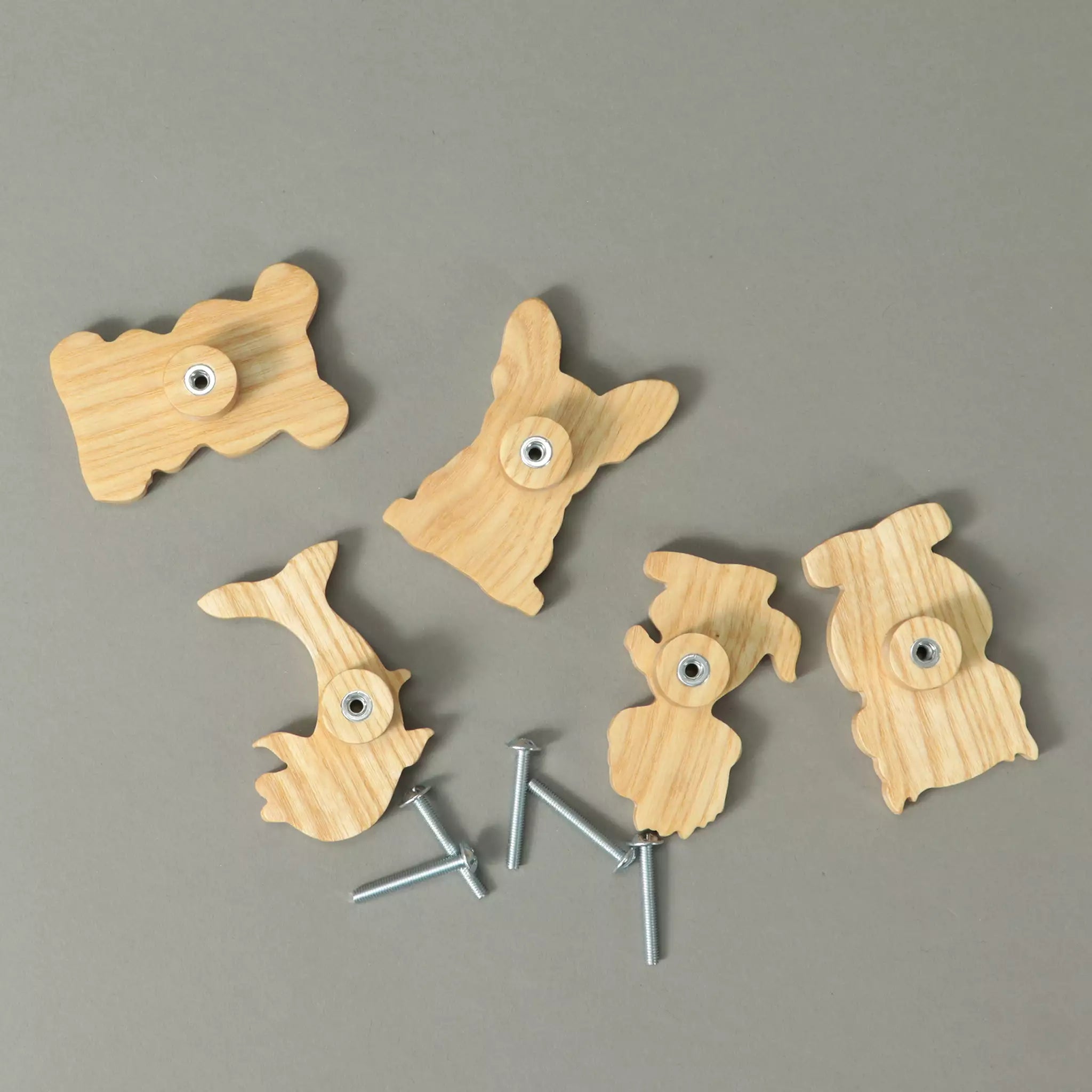 Backs of the knobs in solid ash showing the threaded metal inserts, with the mounting screws beside them