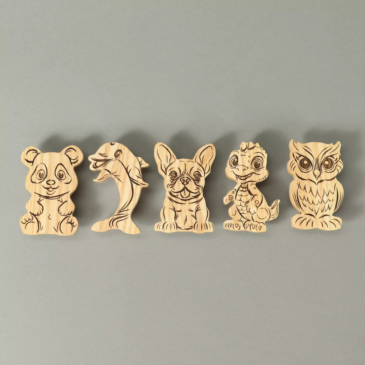 The five knobs in solid ash lined up side by side: panda, dolphin, French bulldog, baby dragon and owl