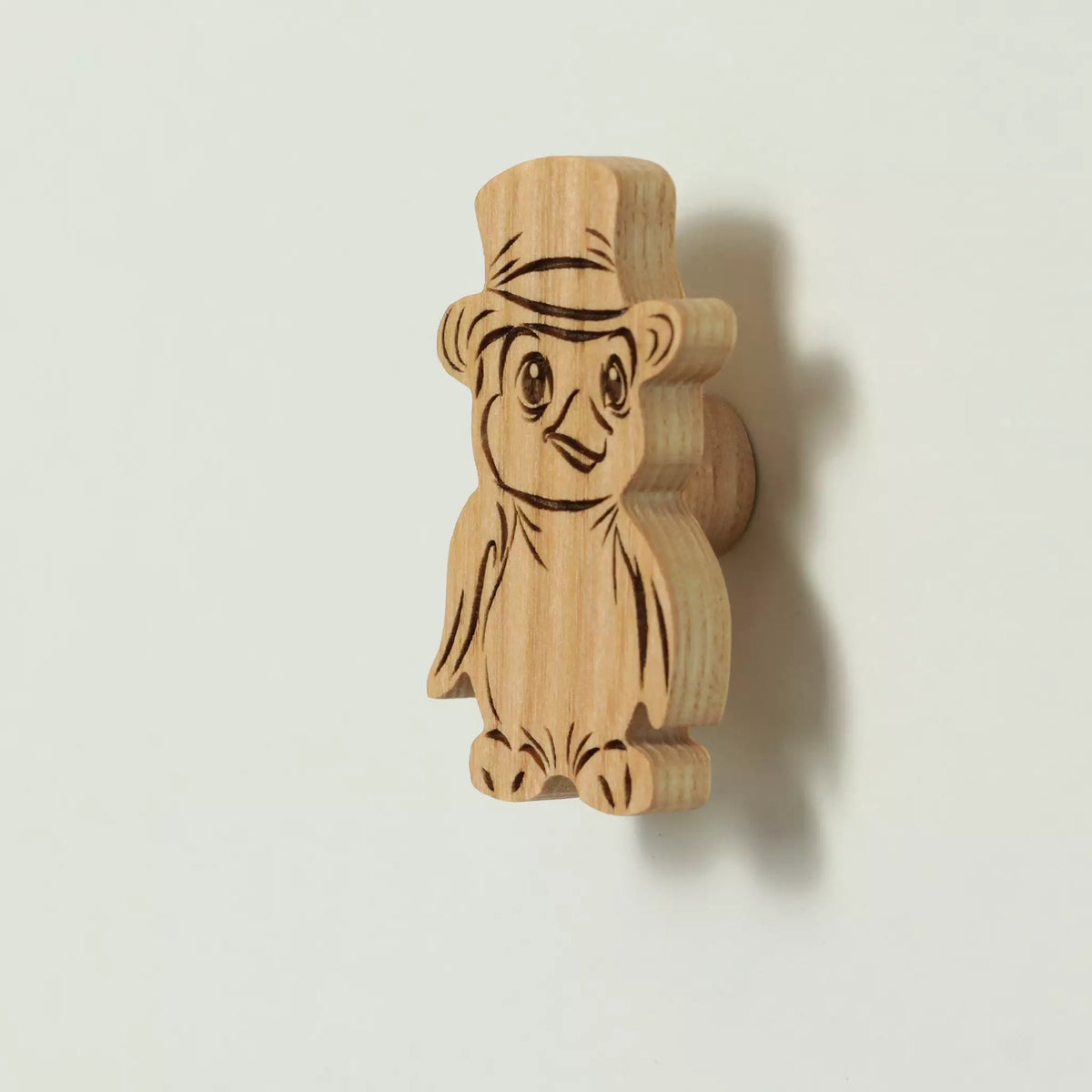 Penguin cabinet knob in solid ash, wearing a hat, engraved and cut to the outline of the animal