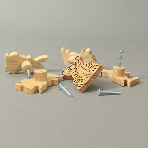 Animal knobs in solid ash lying on a grey background with the mounting screws beside them