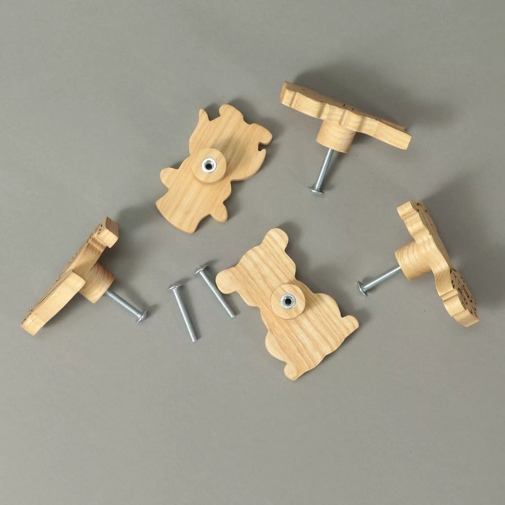 Backs of the animal knobs in solid ash with the mounting screws, on a grey background