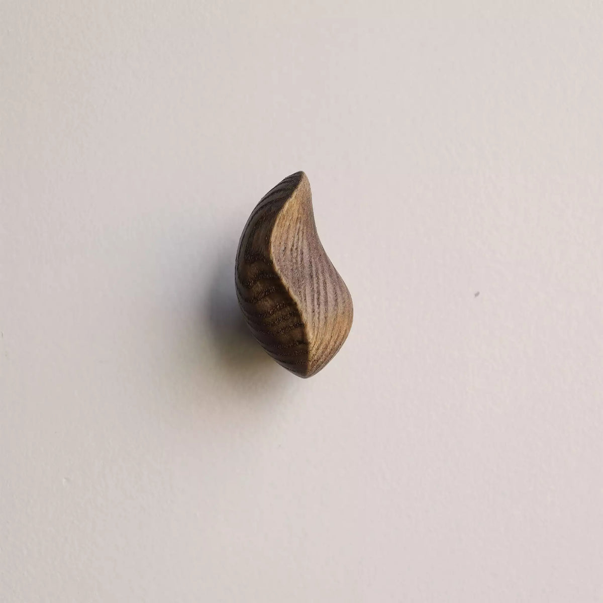 Crescent hook in the walnut finish, seen from the side against the wall