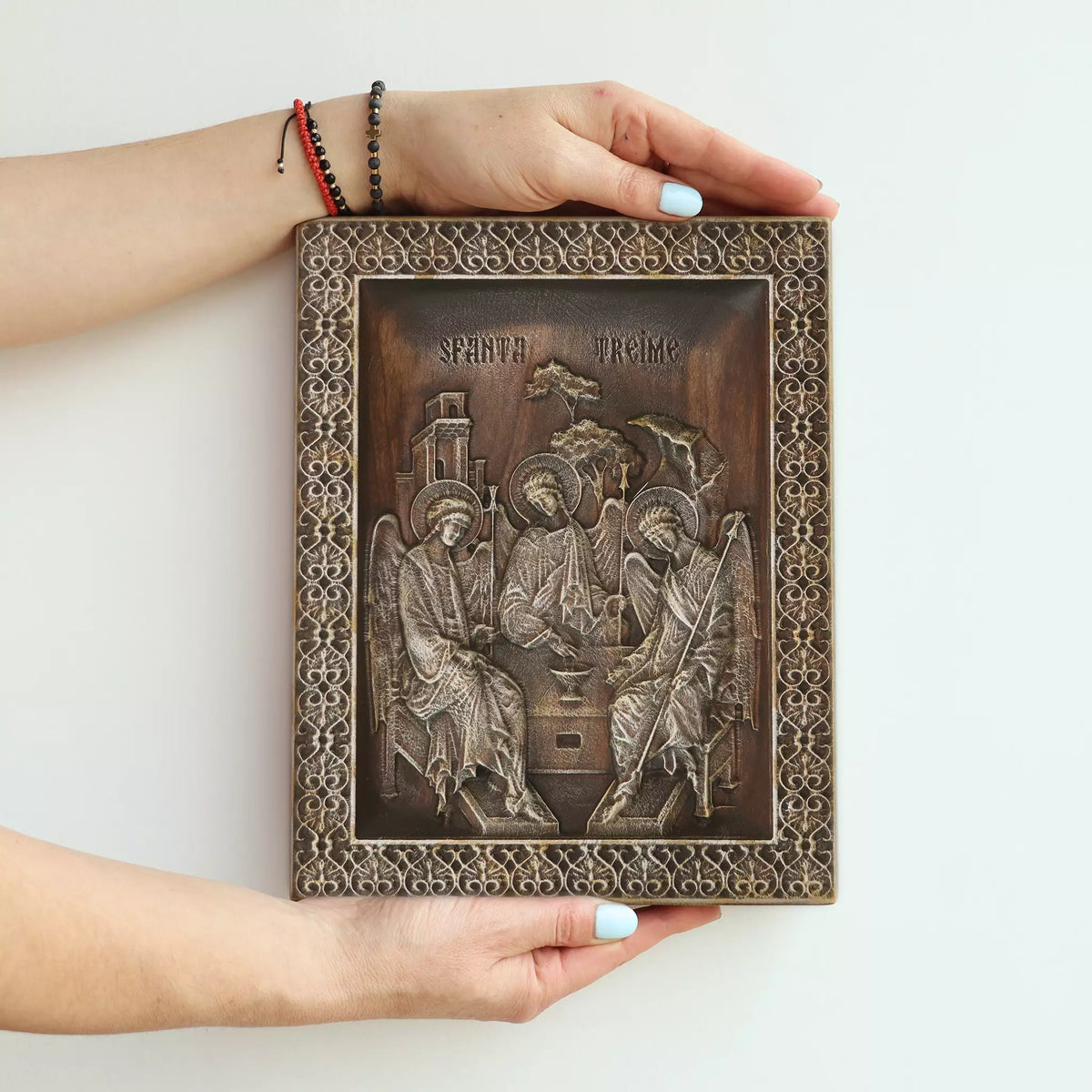 Two hands holding the icon, showing its size against an adult's hands