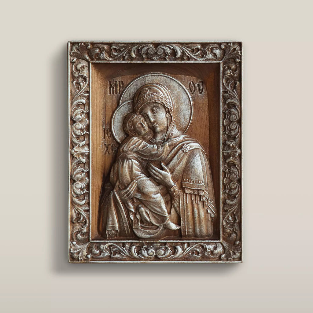 Carved wooden icon of the Virgin Mary holding the Child cheek to cheek, set within a carved floral border