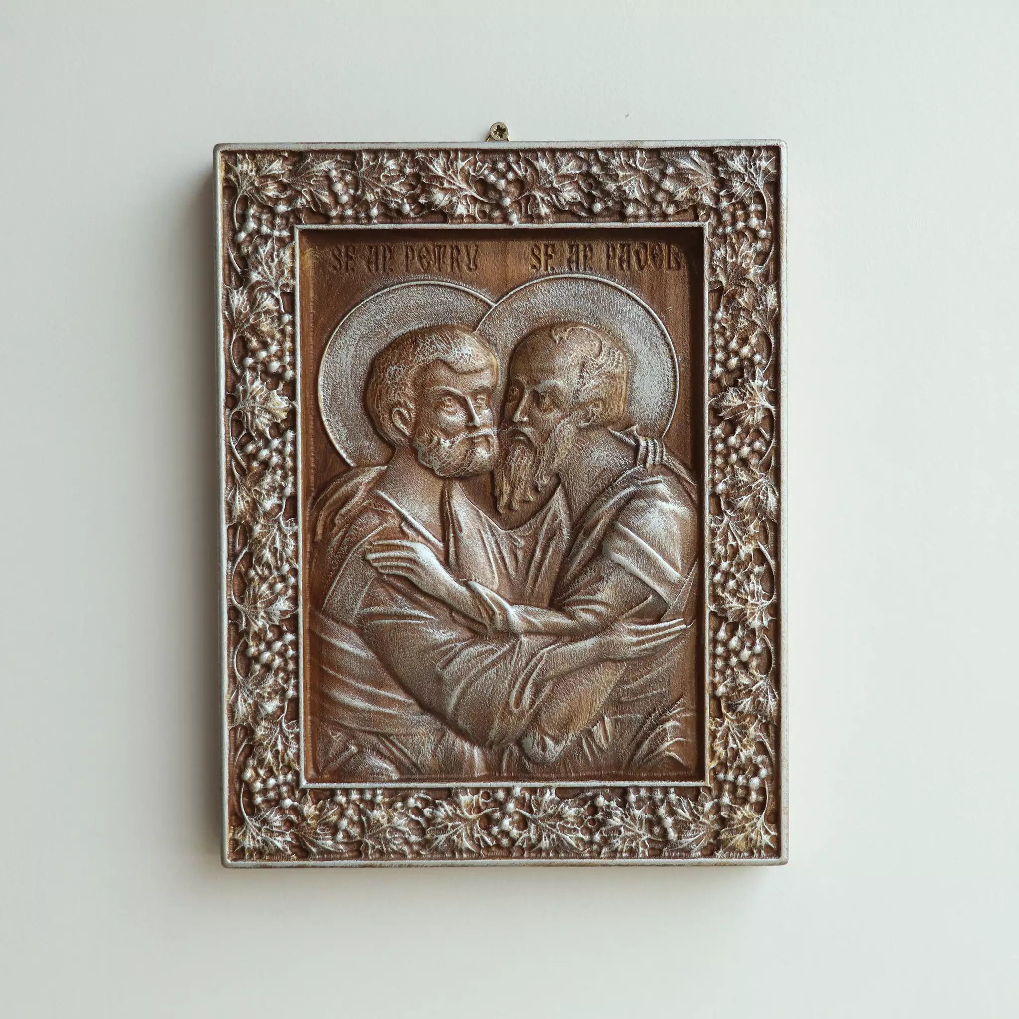 The icon hanging flat on a wall, with the metal hanger visible at the top