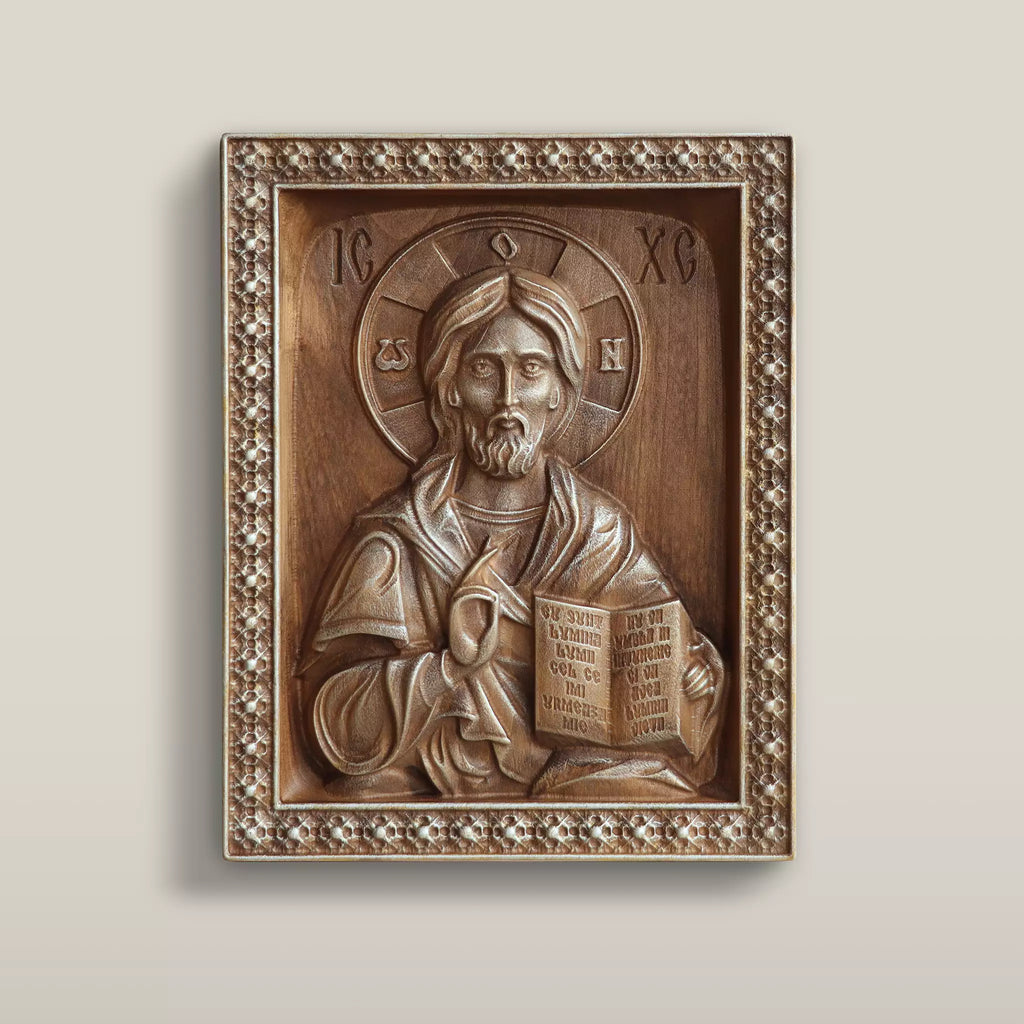 Carved wooden icon of Christ Pantocrator blessing and holding the open Gospel, set within a carved rosette border