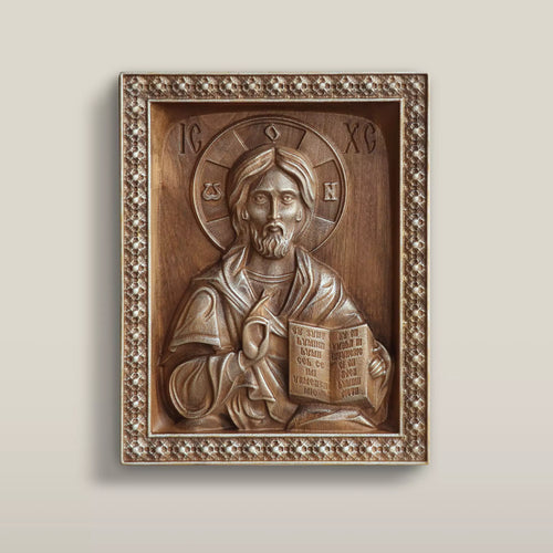 Carved wooden icon of Christ Pantocrator blessing and holding the open Gospel, set within a carved rosette border