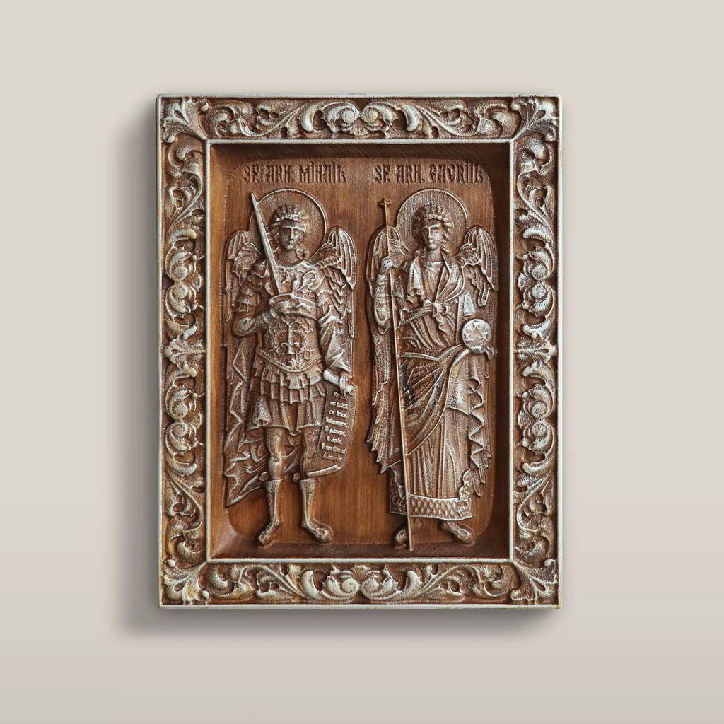 Carved wooden icon of the Archangels Michael and Gabriel standing side by side within a carved vine border