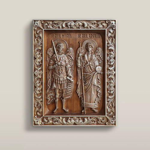 Carved wooden icon of the Archangels Michael and Gabriel standing side by side within a carved vine border