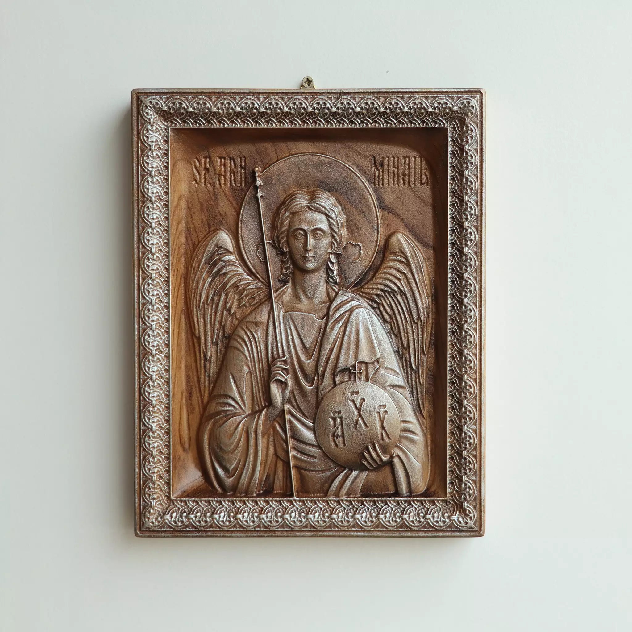 Carved wood icon of the Archangel Michael seen straight on, showing the carved frame and the Romanian inscription