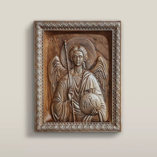 Carved wood icon of the Archangel Michael hanging on a pale wall, seen from the front