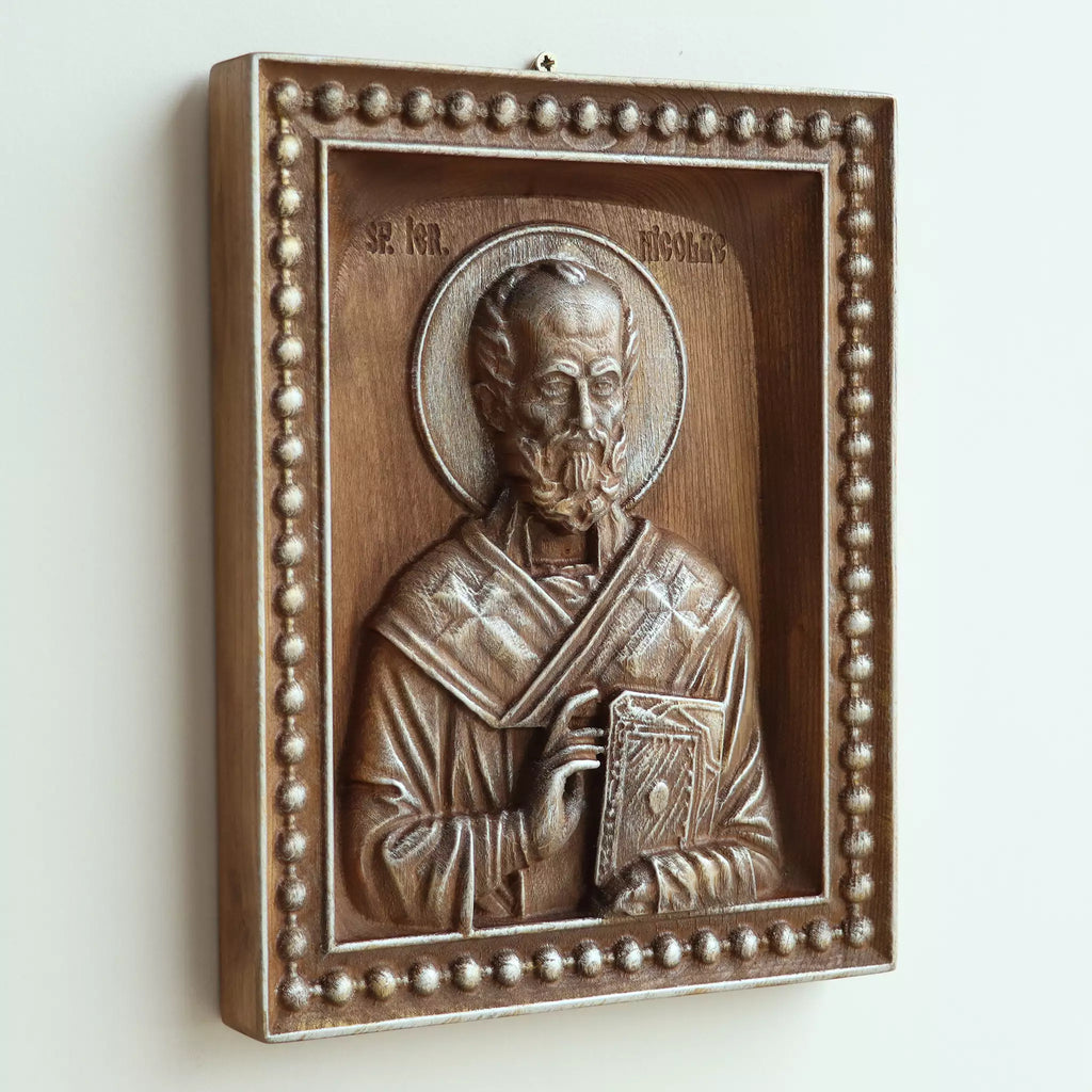 The icon seen at an angle on a white wall, showing the depth of the carved frame