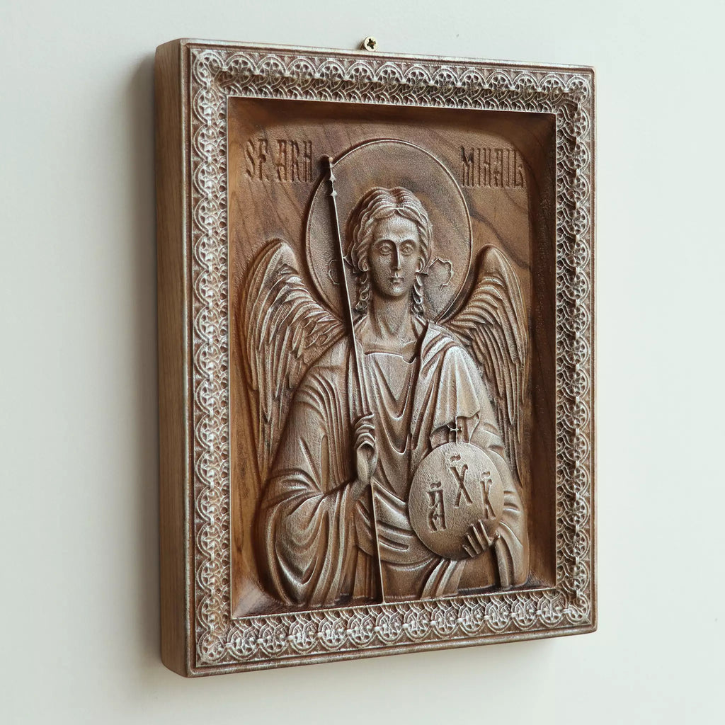Carved wood icon of the Archangel Michael seen at an angle from above, with light raking across the carving