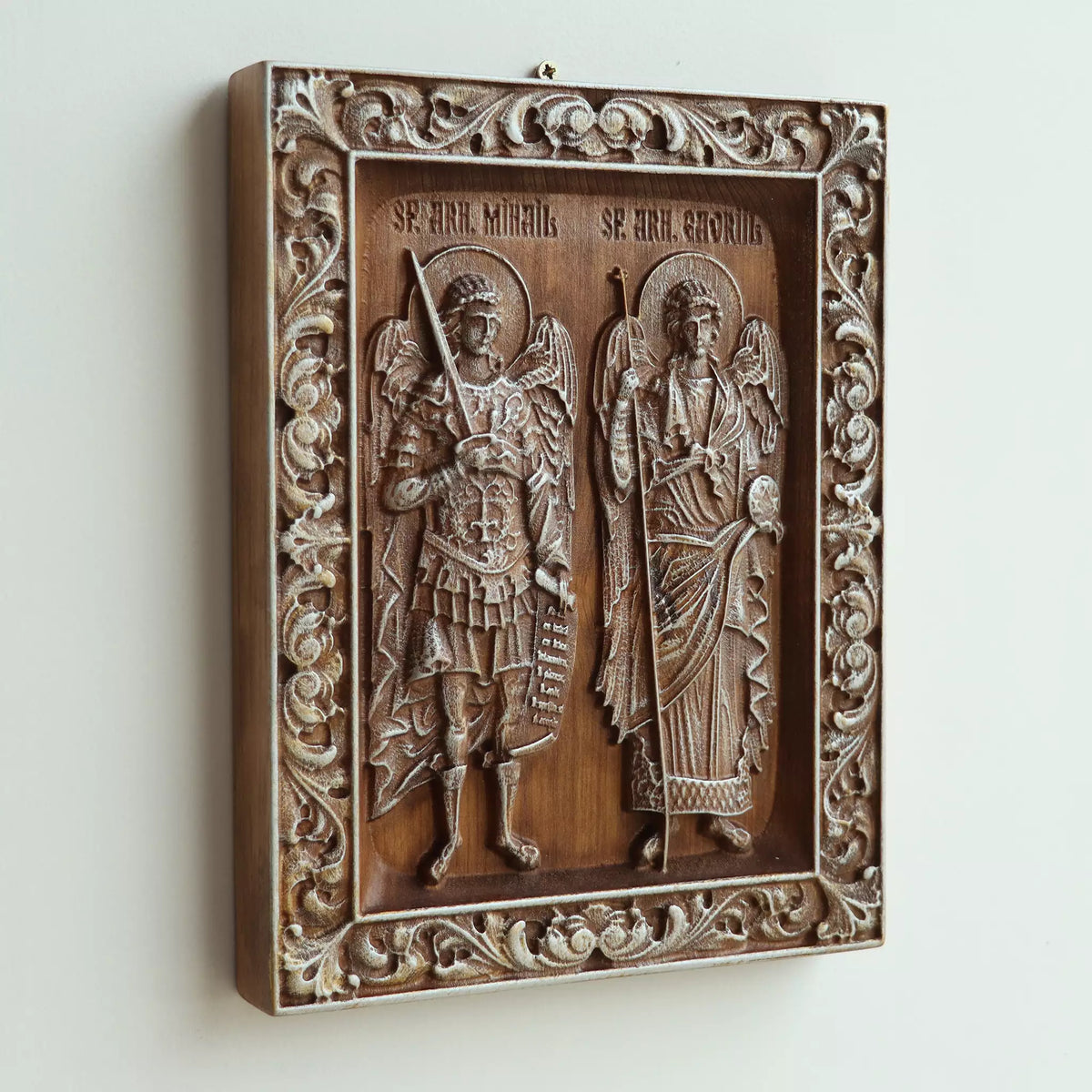 The icon seen at an angle on a white wall, showing the depth of the carved frame