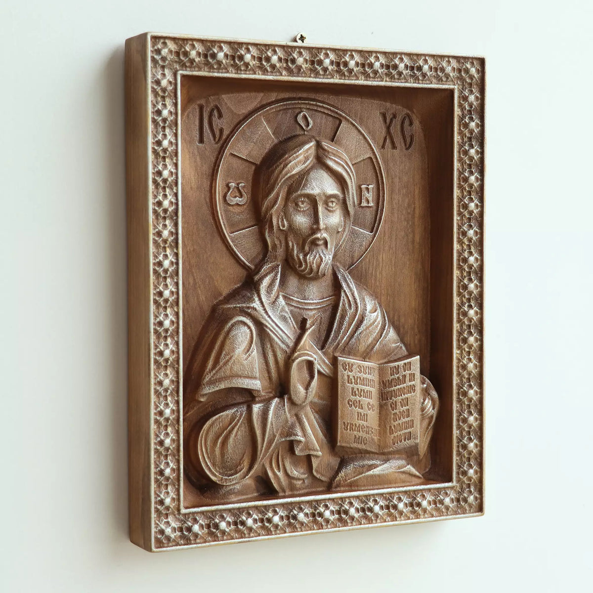 The icon seen at an angle on a white wall, showing the depth of the carved frame