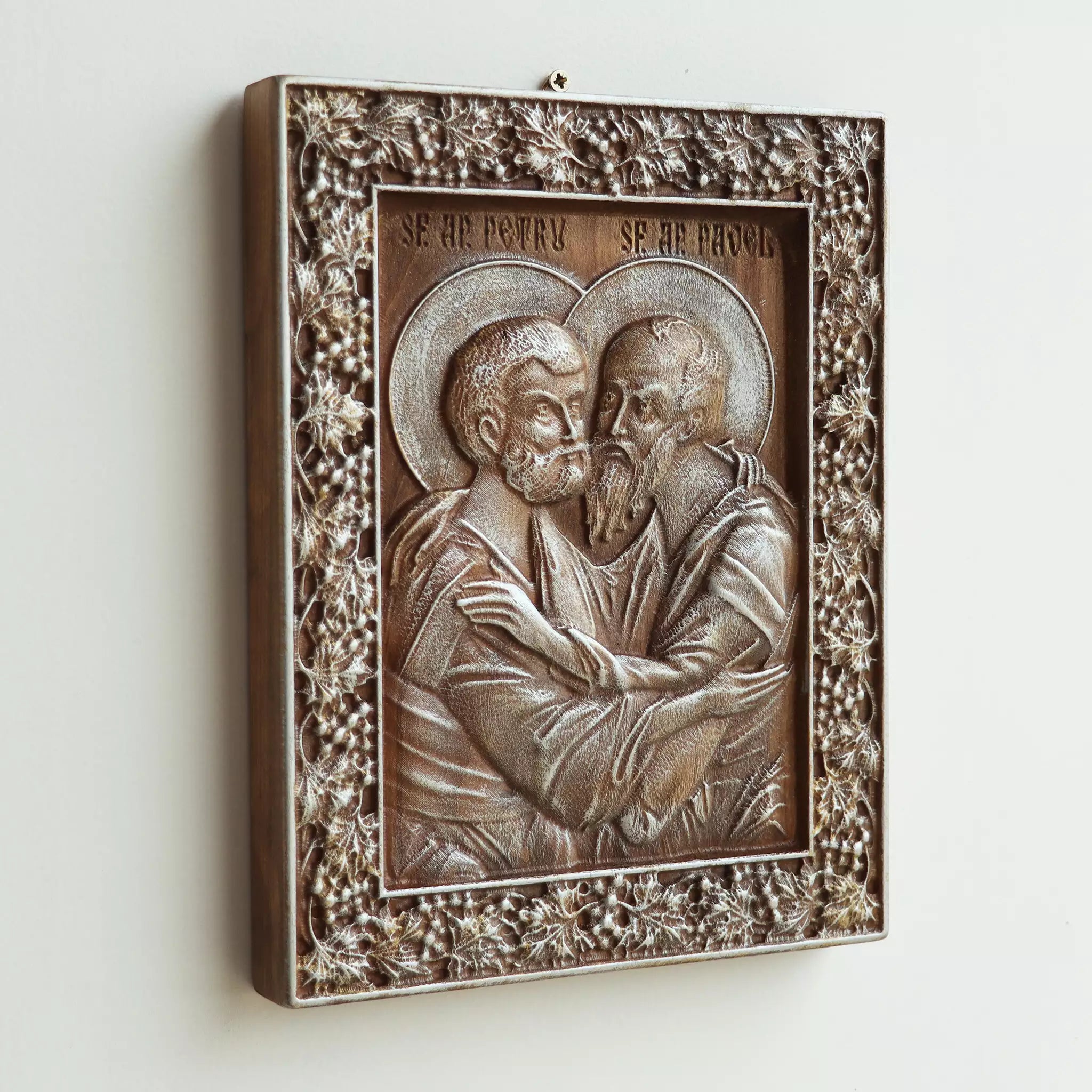 The icon seen at an angle on a white wall, showing the depth of the carved frame