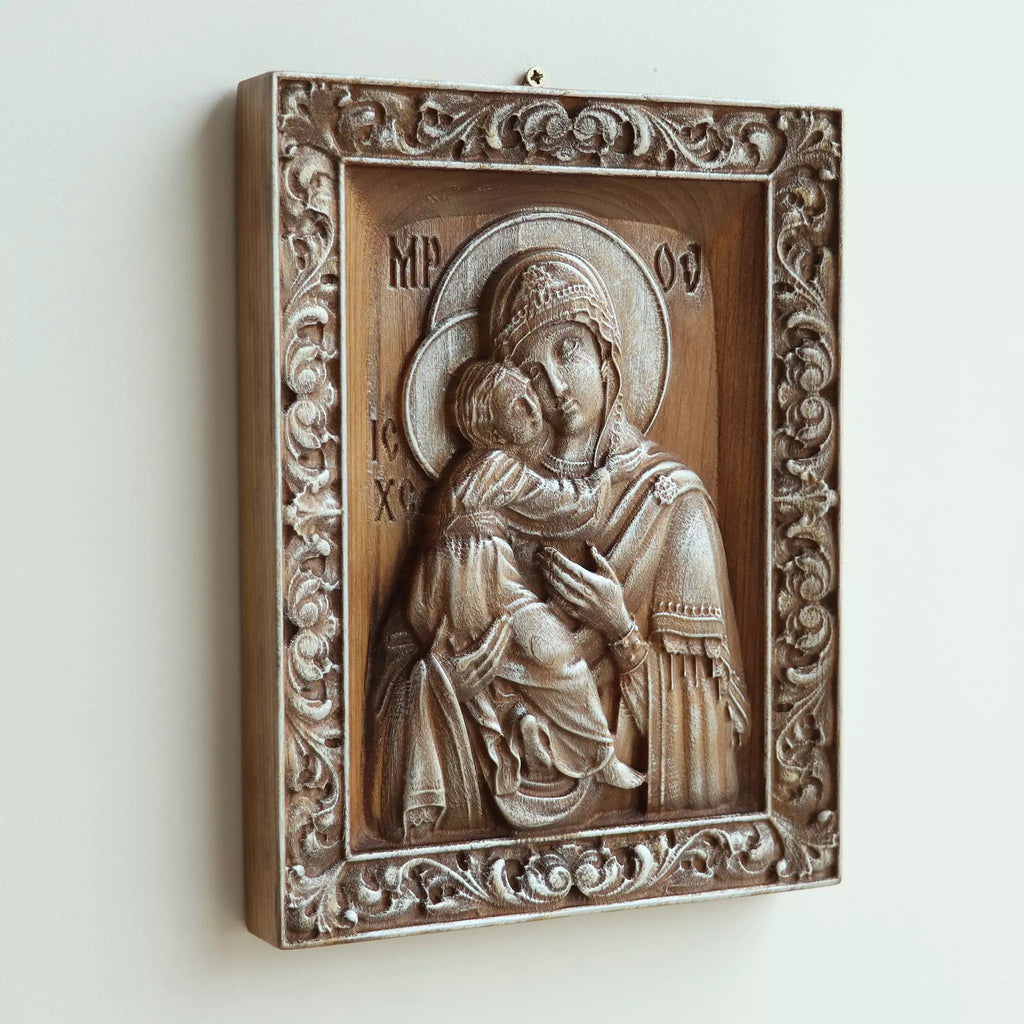 The icon seen at an angle on a white wall, showing the depth of the carved frame