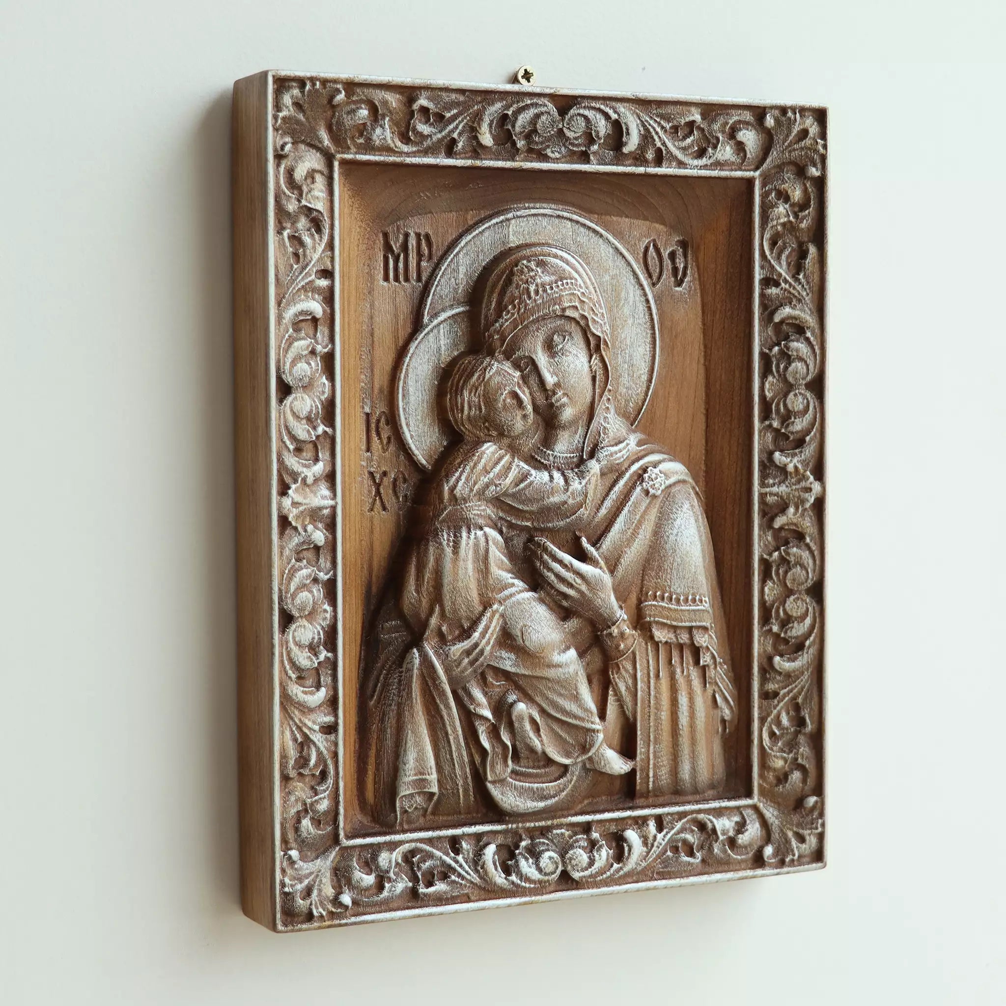The icon seen at an angle on a white wall, showing the depth of the carved frame