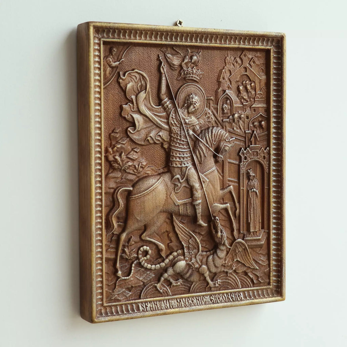 The icon seen at an angle on a white wall, showing the depth of the carved scene