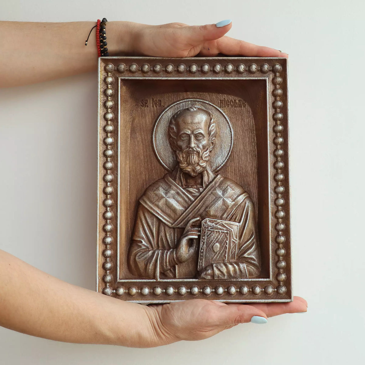 Two hands holding the icon, showing its size against an adult's hands