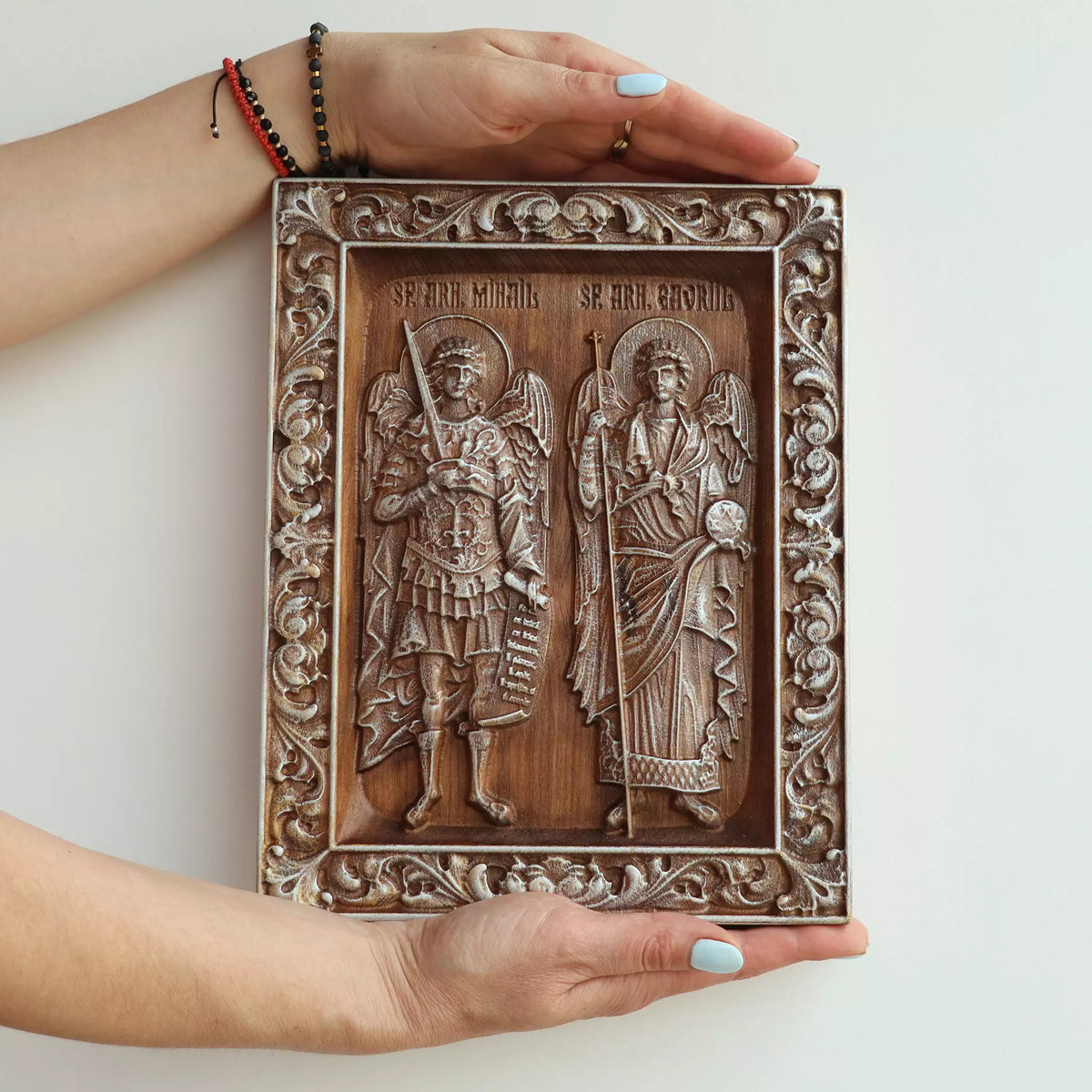 Two hands holding the icon, showing its size against an adult's hands