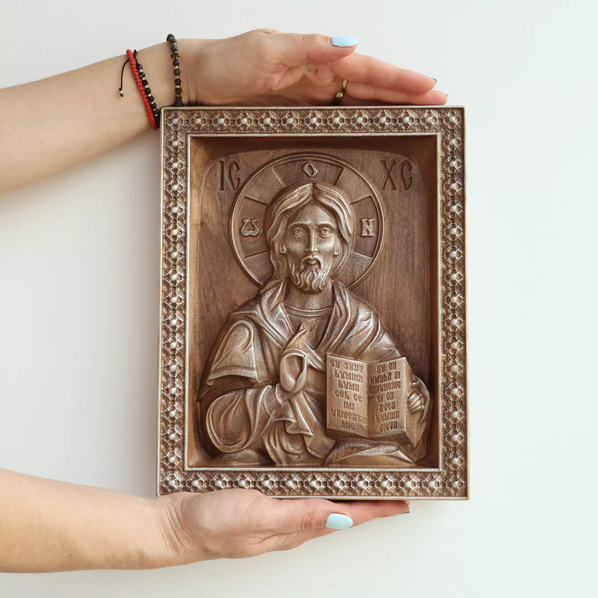 Two hands holding the icon, showing its size against an adult's hands