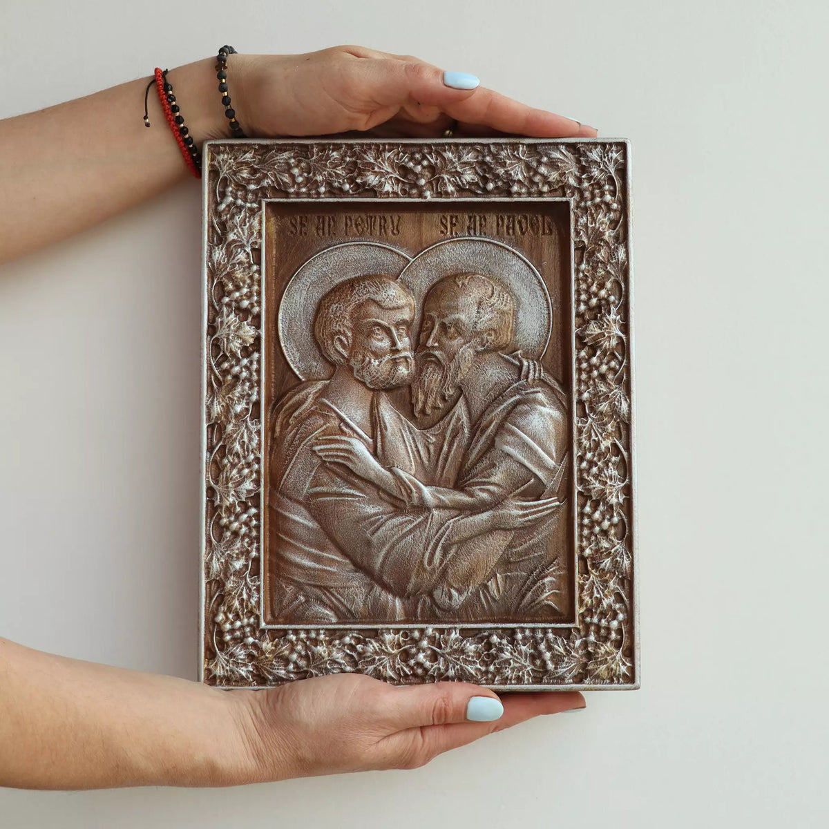 Two hands holding the icon, showing its size against an adult's hands