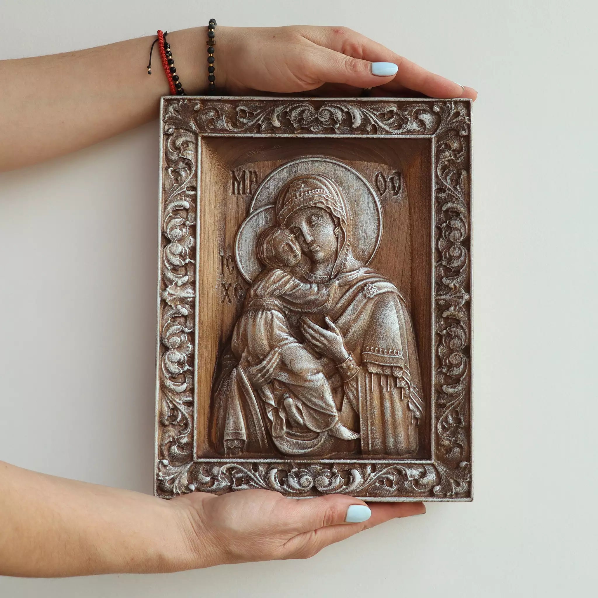 Two hands holding the icon, showing its size against an adult's hands