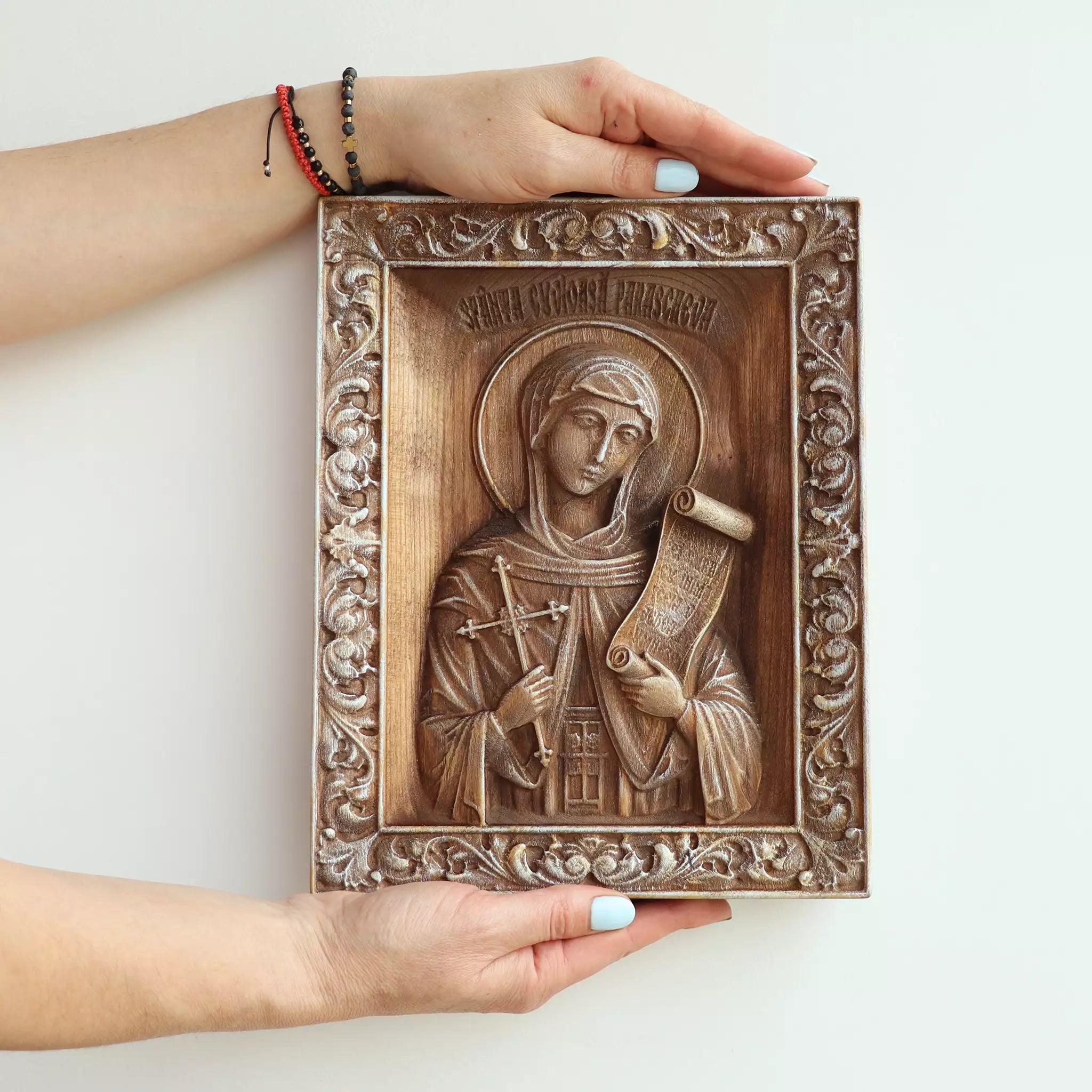 Two hands holding the icon, showing its size against an adult's hands
