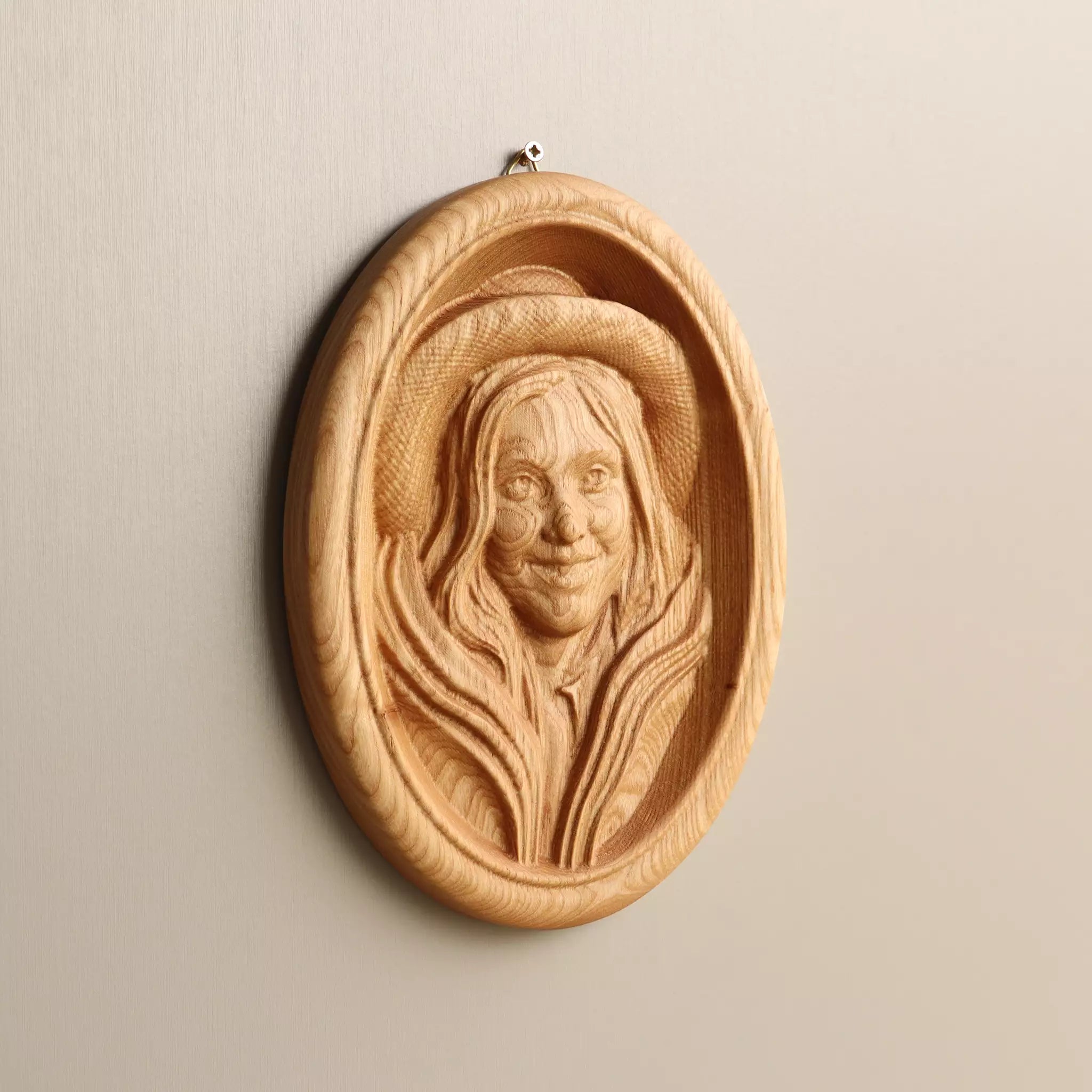 Carved oval wood portrait in the natural oiled finish, the ash grain running through the face
