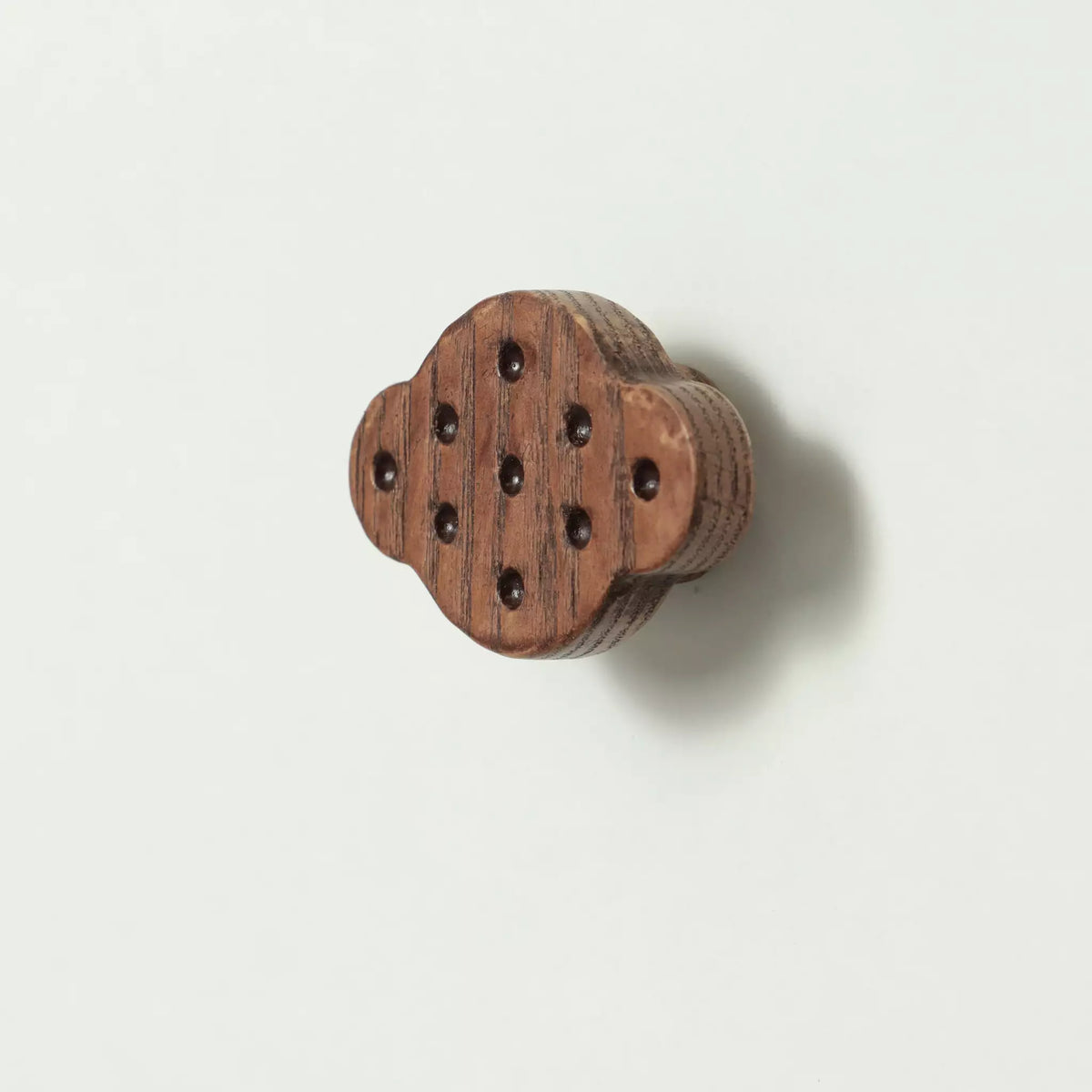 Dimpled oval cabinet knob in the Walnut finish seen at an angle with the base visible behind it
