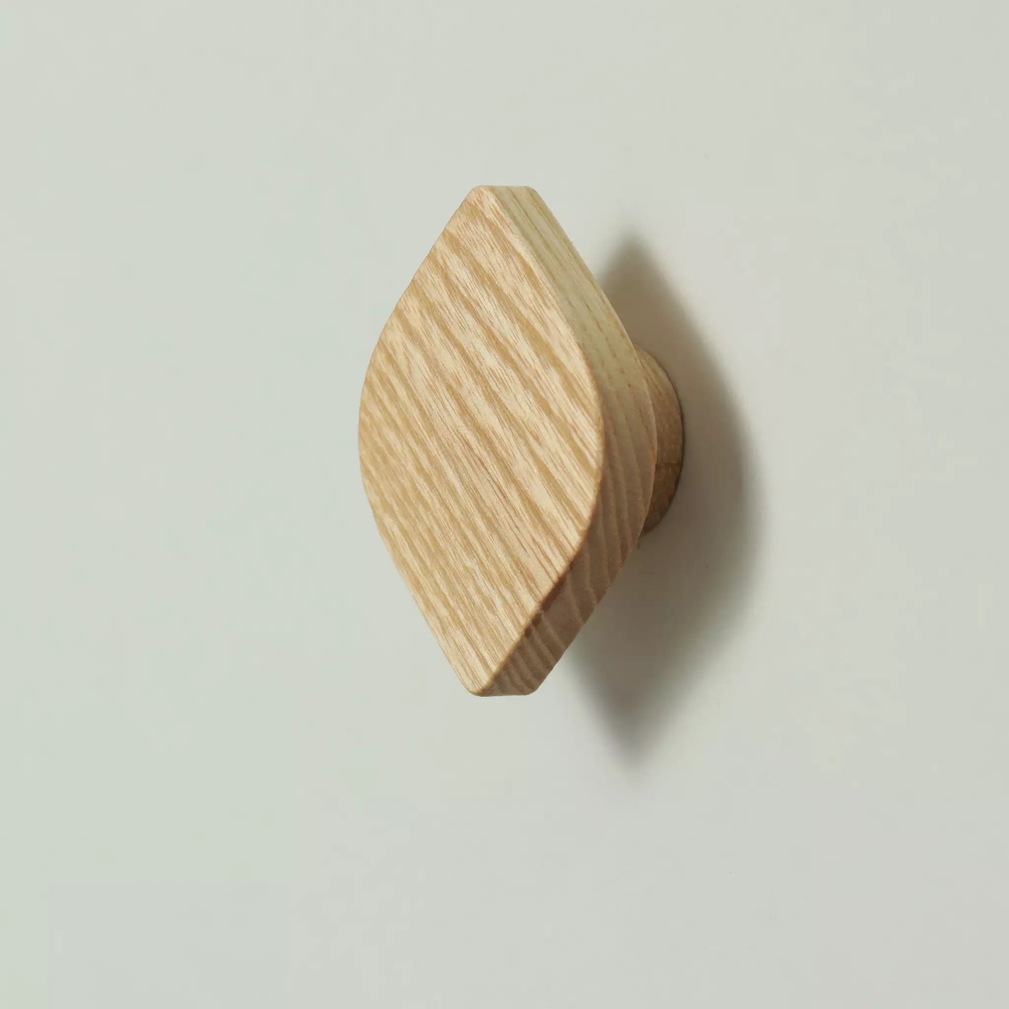 Solid ash leaf cabinet knob seen from above at an angle, showing the rounded edges