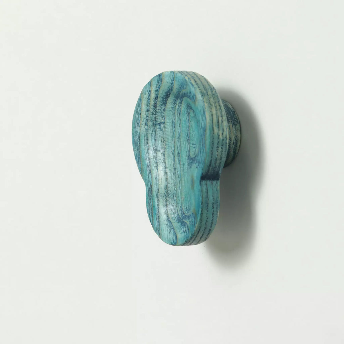 Shell cabinet knob in the Blue finish seen from the side, with the base visible behind it