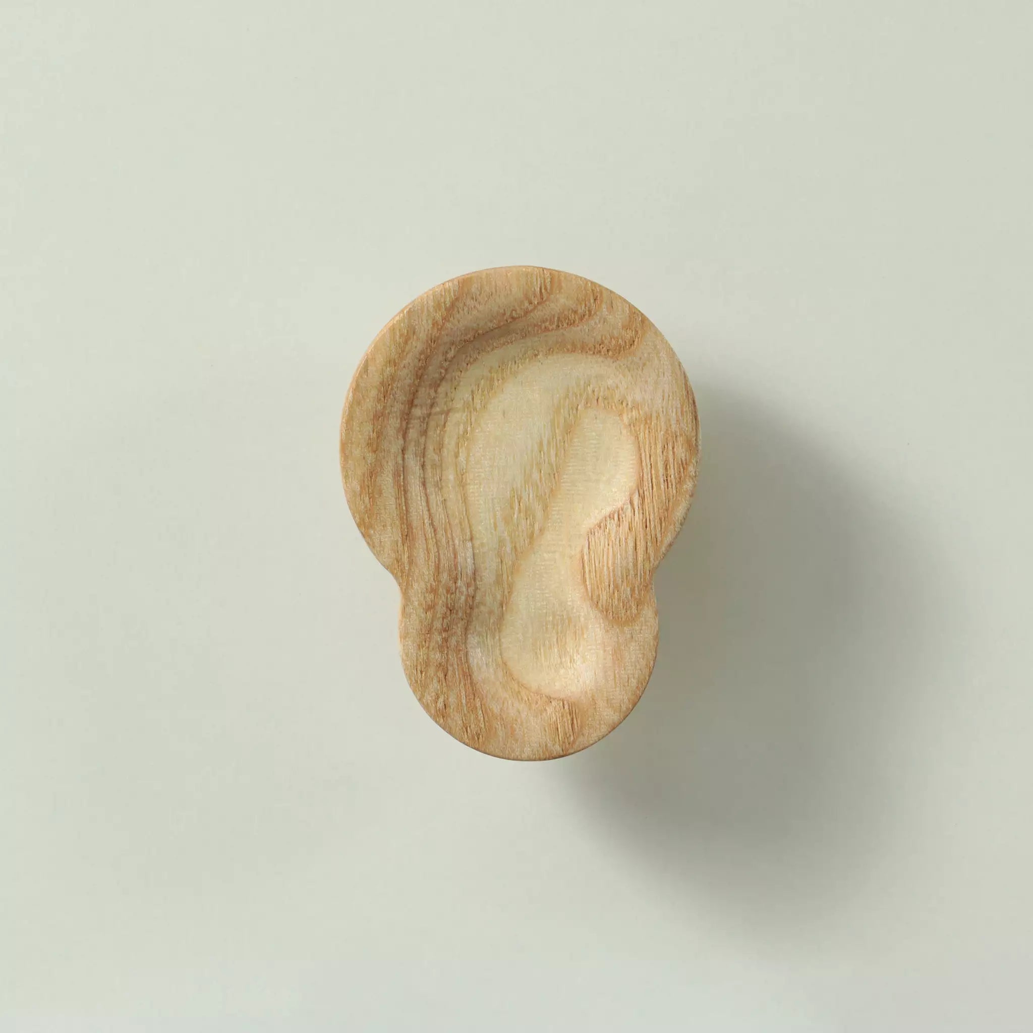 Unfinished solid ash shell cabinet knob seen from the front, showing the carved hollow across the face
