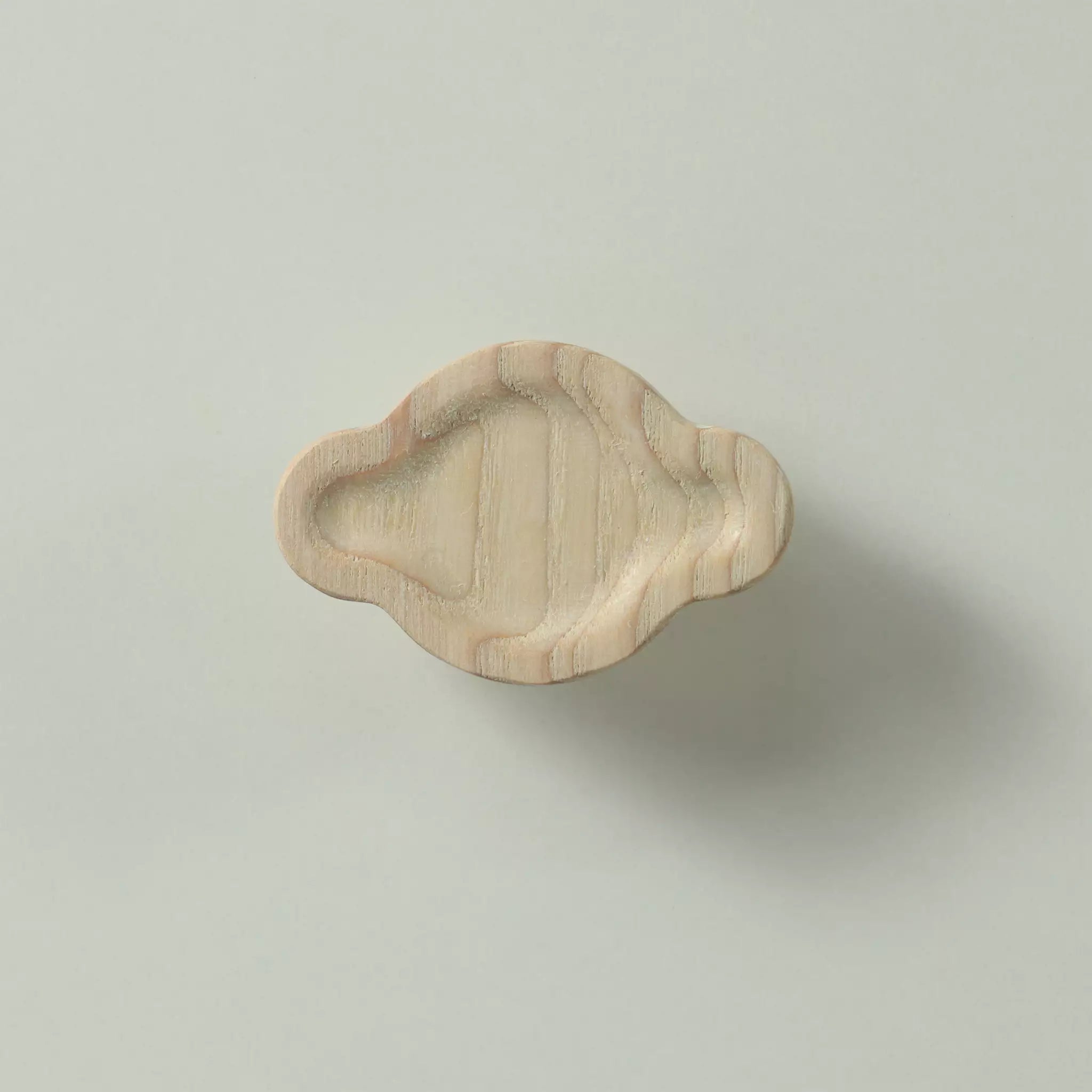 Unfinished solid ash sculpted cloud cabinet knob seen from the front, showing the hollow and the small scoop at one end