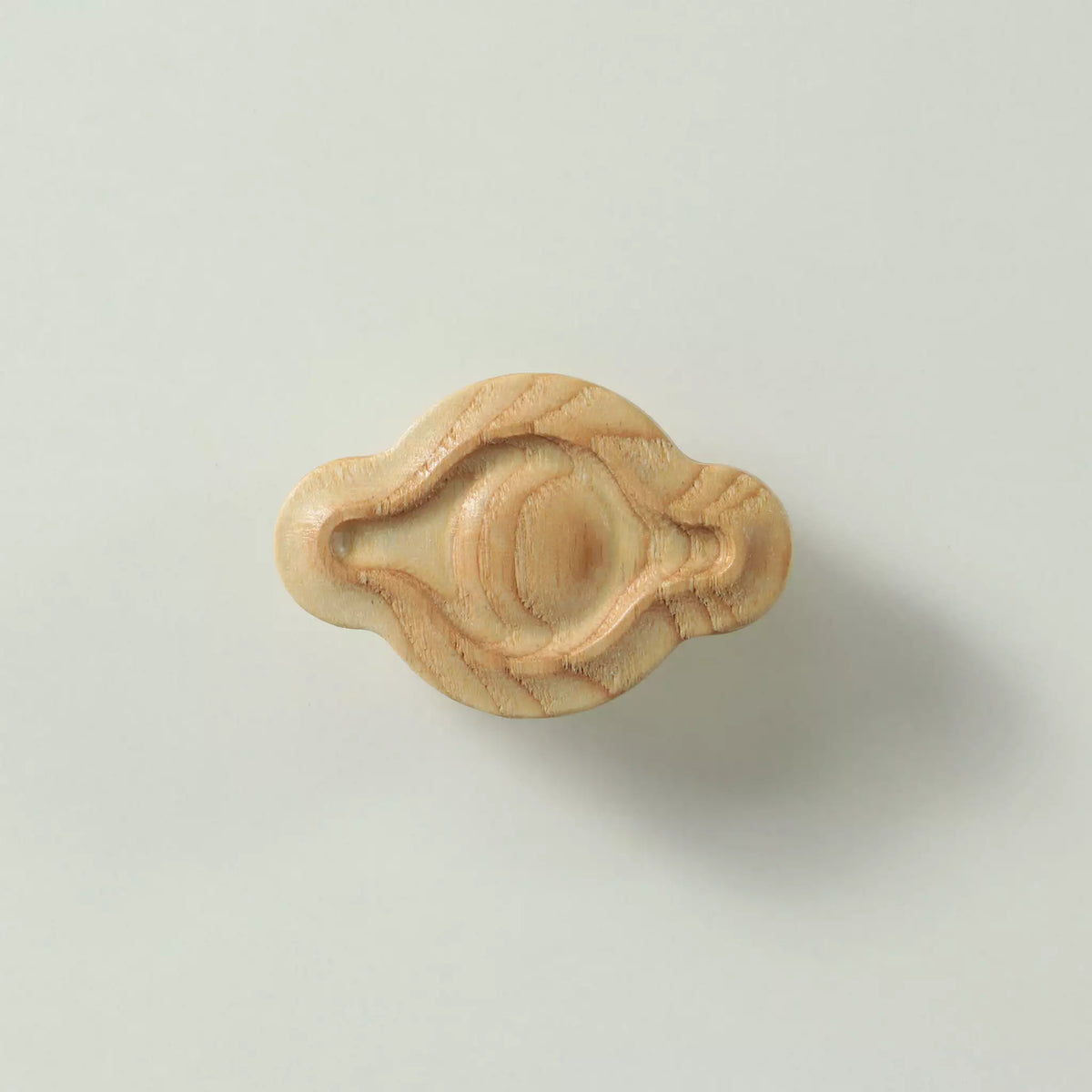 Unfinished solid ash petal cabinet knob seen from the front, showing the domed centre and the carved groove