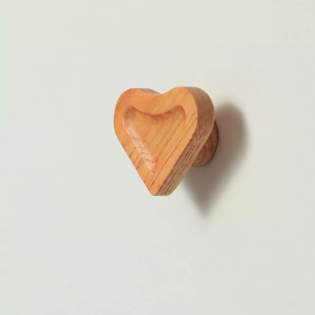 Scooped heart cabinet knob in the Orange finish seen at an angle, with the base visible behind it