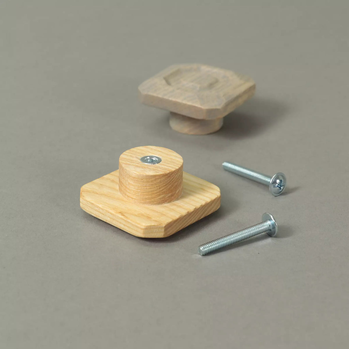 Back of a stepped octagon cabinet knob showing the base and the threaded metal insert, with a second knob and the mounting hardware behind