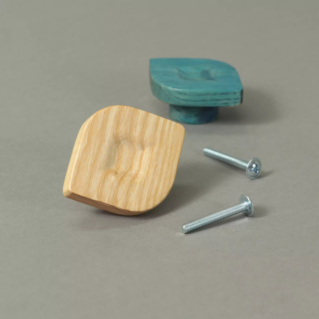 Unfinished and Blue twist cabinet knobs beside the mounting hardware, on a grey background