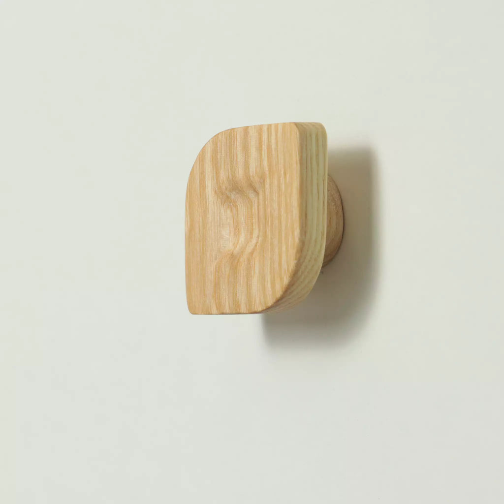 Unfinished solid ash twist cabinet knob seen from the side, with the base visible behind it