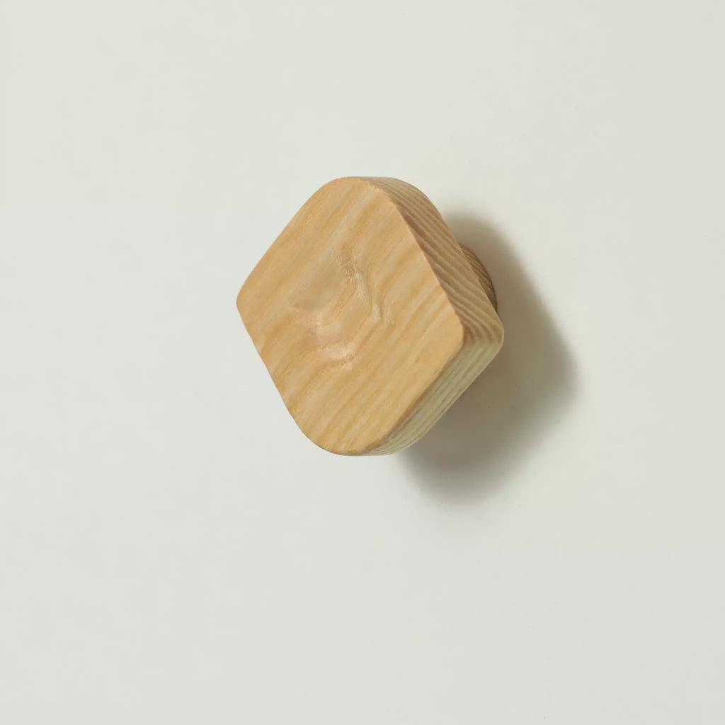 Unfinished solid ash twist cabinet knob tilted to show the thickness of the block