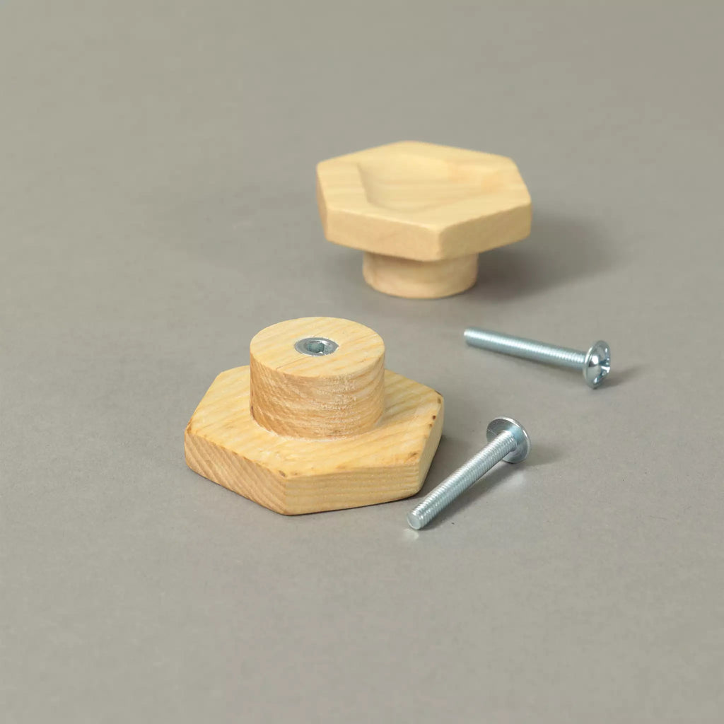 Back of a carved hexagon cabinet knob showing the base and the threaded metal insert, with a second knob and the mounting hardware behind