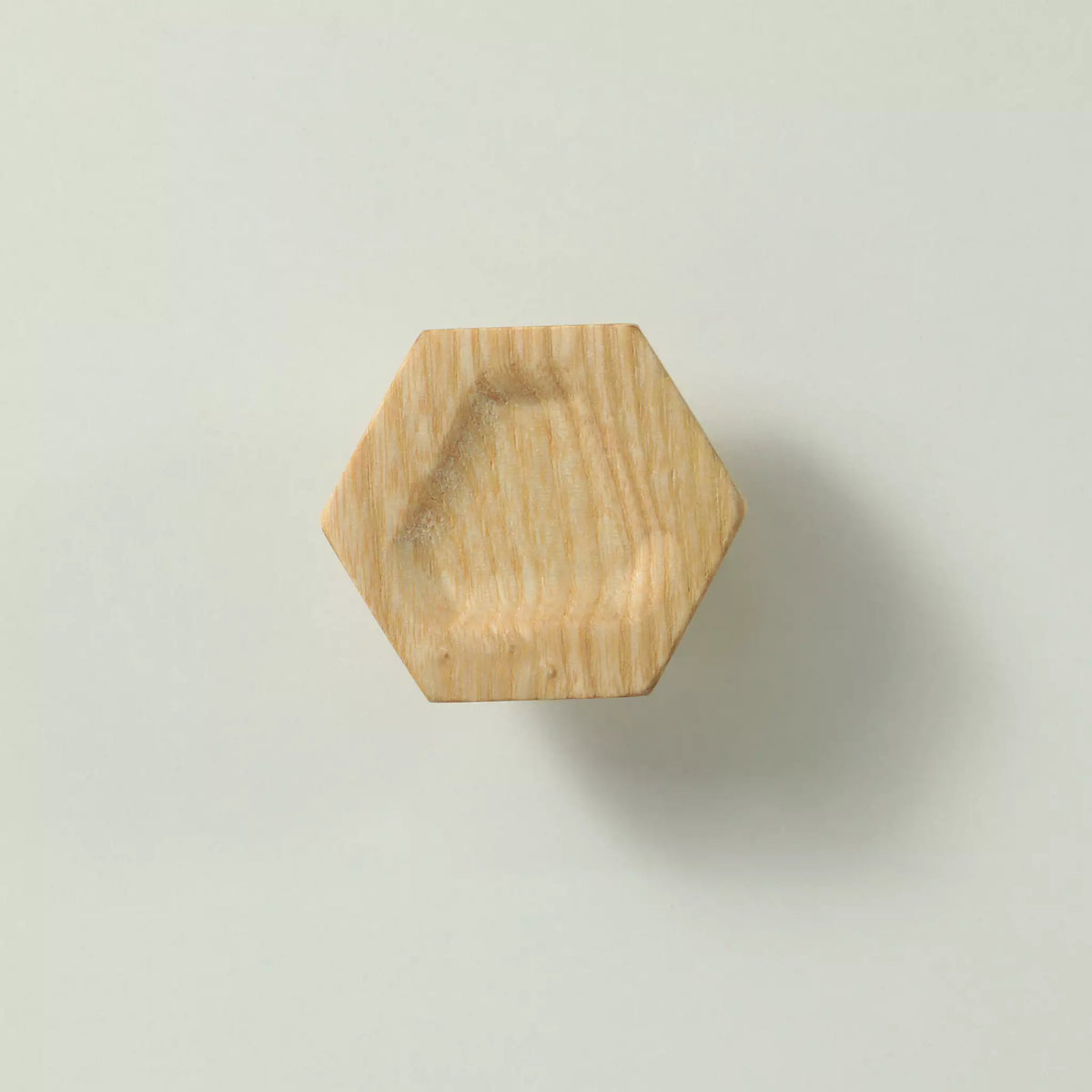 Unfinished solid ash carved hexagon cabinet knob seen from the front, showing the triangular hollow in the face