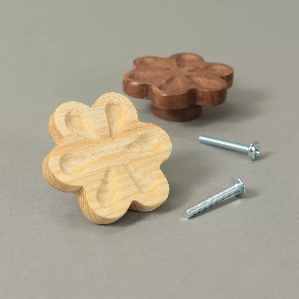 Back of an unfinished carved flower cabinet knob showing the base and the threaded metal insert, with a Walnut knob and the mounting hardware behind