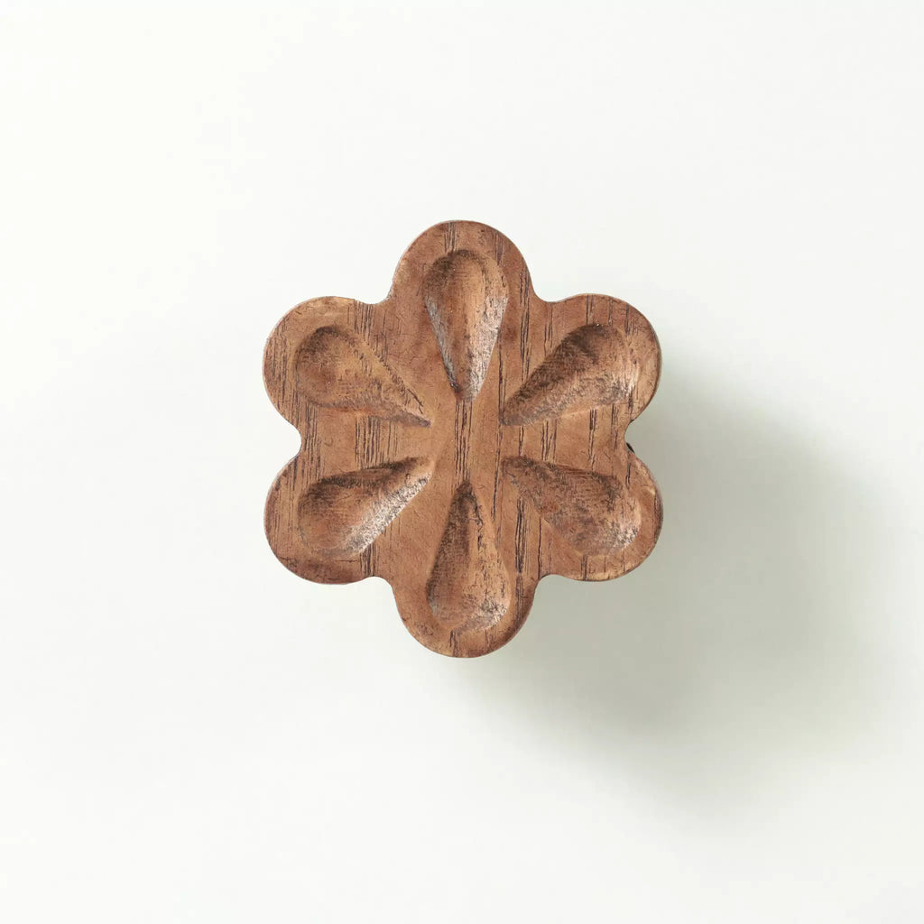 Carved flower cabinet knob in the Walnut finish seen from the front, showing the six hollowed petals