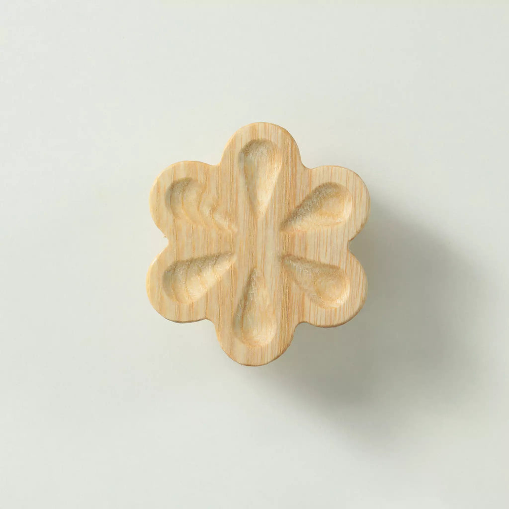Unfinished solid ash carved flower cabinet knob seen from the front, showing the six hollowed petals