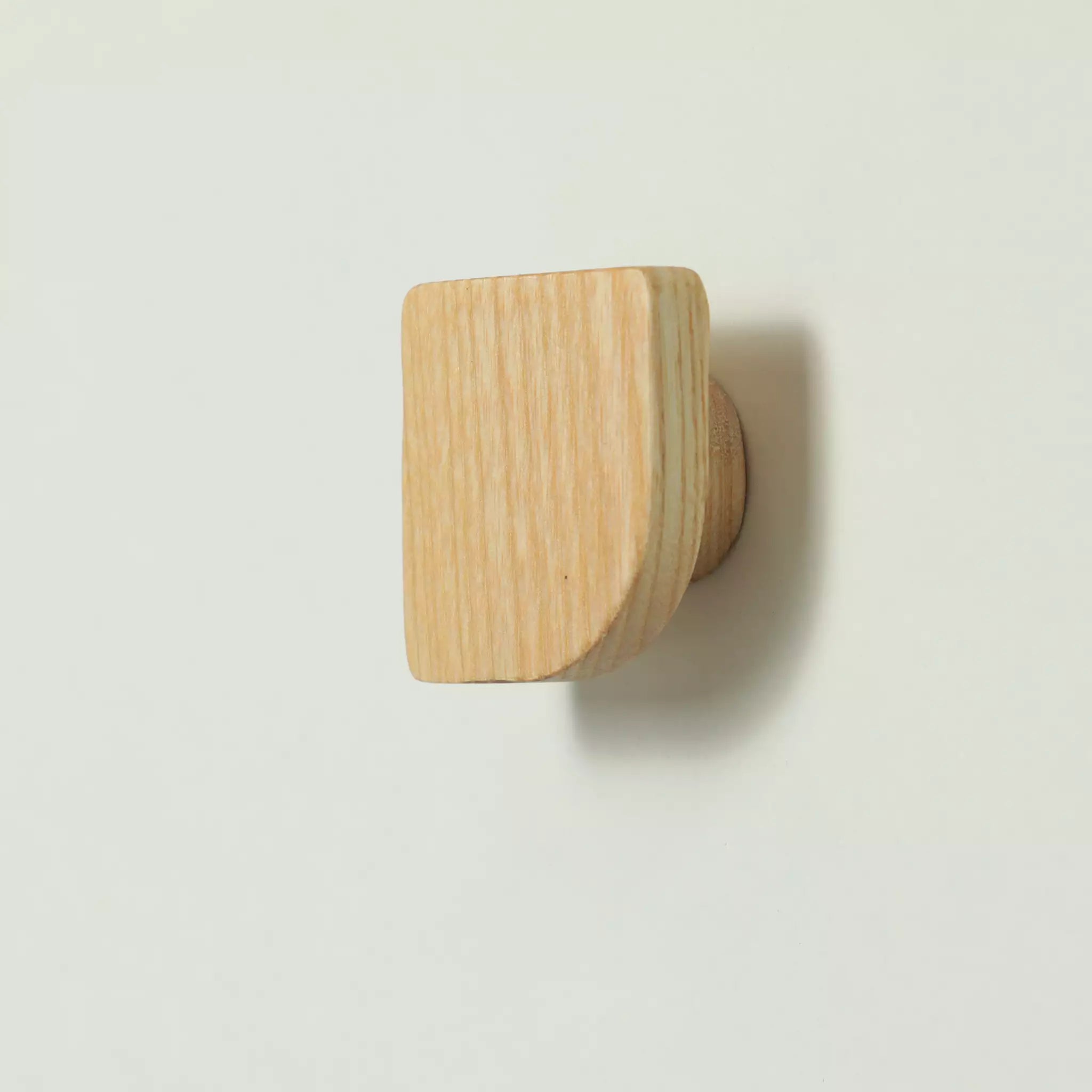 Fan-shaped ash cabinet knob in bare wood, seen at an angle