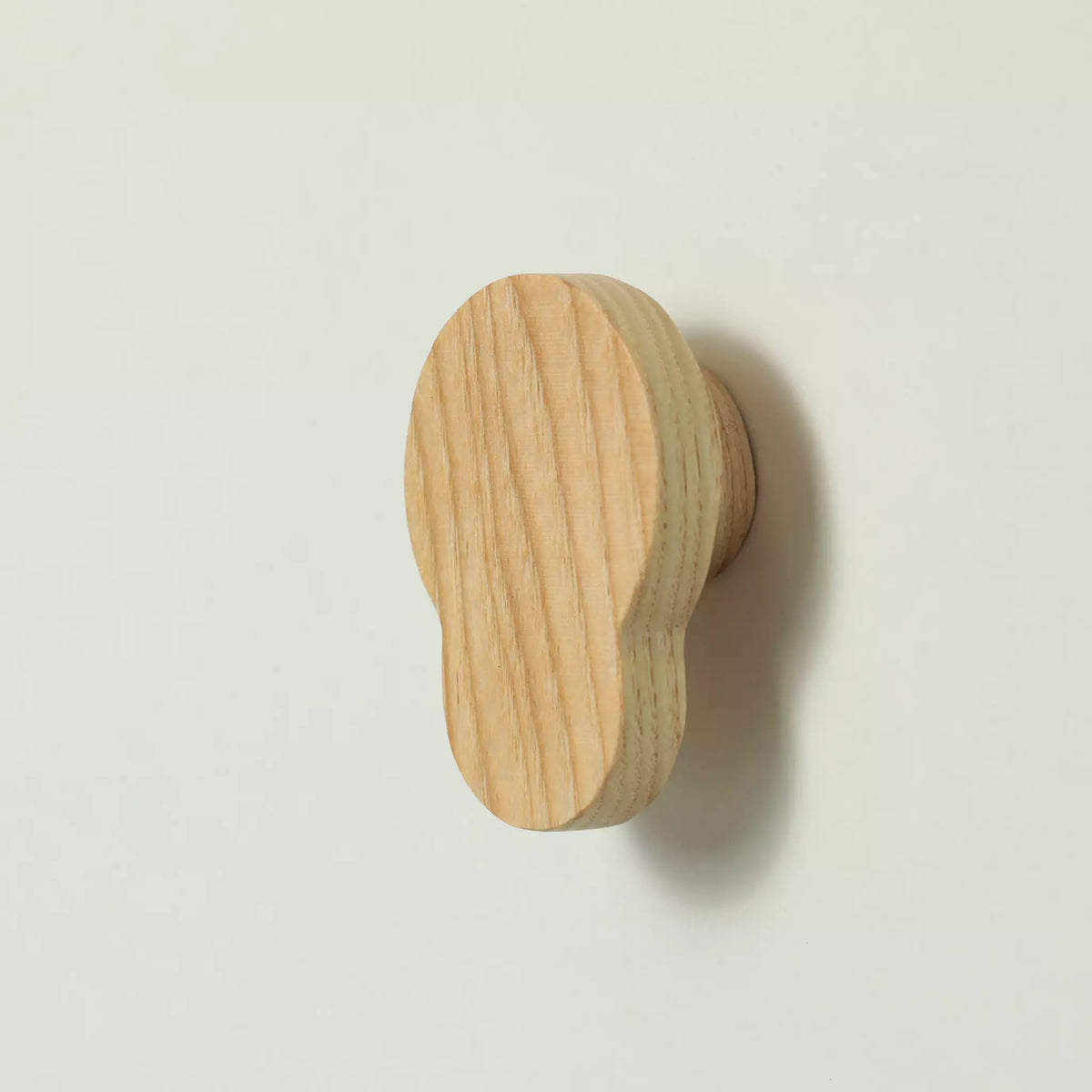 Unfinished solid ash double circle cabinet knob seen from the side with the base visible behind it