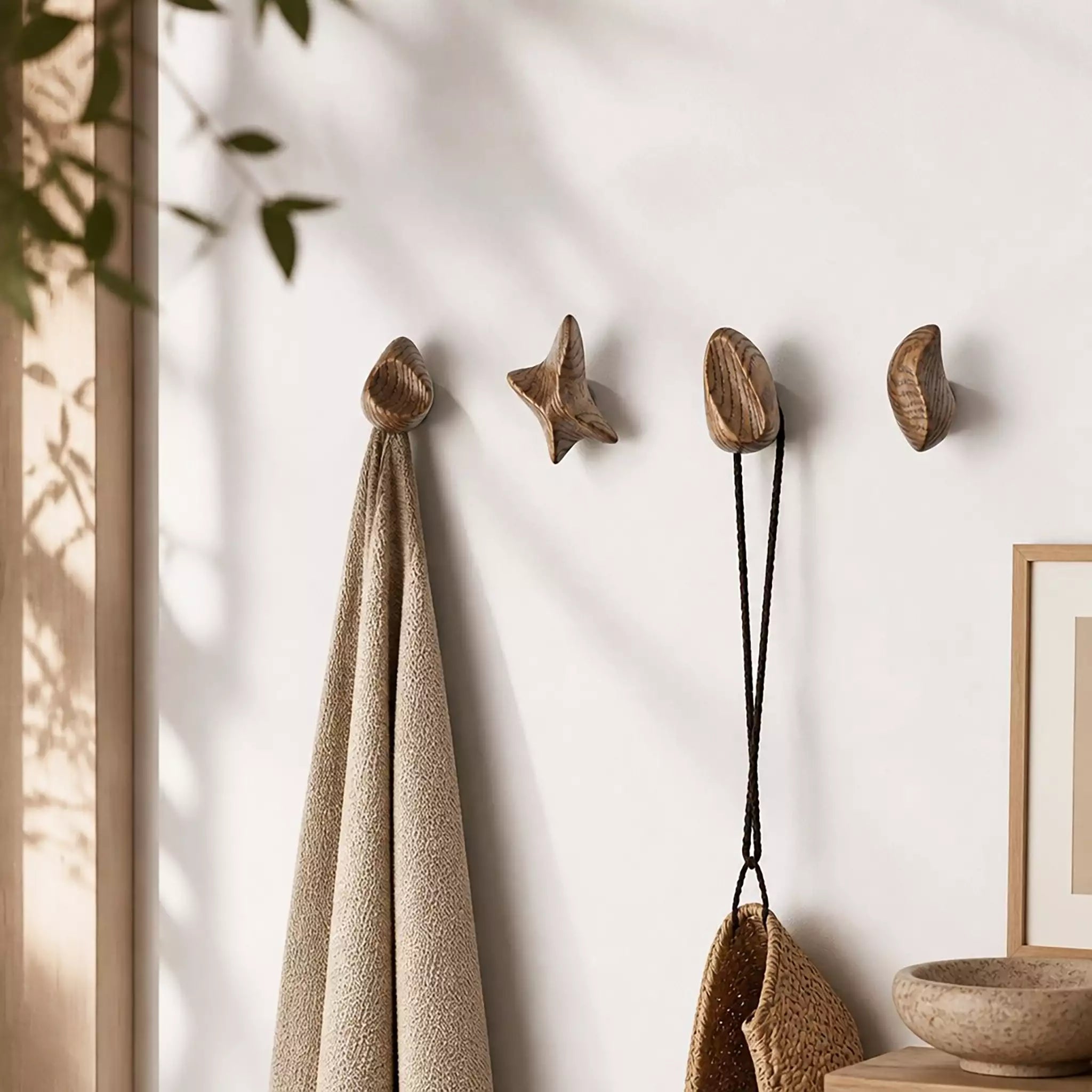 The four hooks on a hallway wall holding a towel, a bag and a cord, with a framed print alongside
